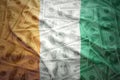 Colorful waving ivorian flag on a dollar money background