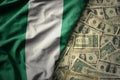 colorful waving national flag of nigeria on a american dollar money background. finance concept