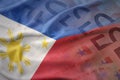 Colorful waving national flag of philippines on a euro money banknotes background.