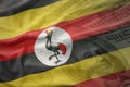Colorful waving national flag of uganda on a american dollar money background.