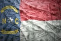 Colorful waving north carolina state flag on a american dollar money background