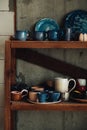 Colorful, white and blue ceramic cups and dishes on shelves of pottery store Royalty Free Stock Photo