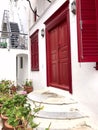 Colorful white house facade with red doors, staircase and shutters on the island of Mykonos Royalty Free Stock Photo