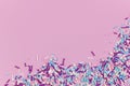 Colorful white, pink, blue and purple sugar sprinkles in shape of balls and sticks on pink background with copy space