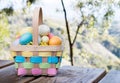 Colorful wicker Easter basket filled with Easter eggs on a picnic table outdoors