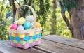 Colorful wicker Easter basket filled with Easter eggs on a picnic table outdoors