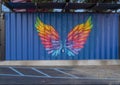 Colorful wings painted on a blue corrugated steel outside wall in Dallas, Texas.