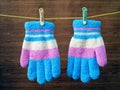 pastel color children winter gloves with green and brown clothespin hanging on a yellow rope clothes line Royalty Free Stock Photo