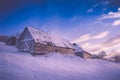 Colorful winter sunrise in the mountains. Fantastic morning glowing by sunlight. View of the snowy forest and old wooden hut cabin Royalty Free Stock Photo