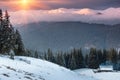 Colorful winter sunrise in the mountains. Fantastic morning glowing by sunlight. View of the snowy forest and old wooden hut cabin Royalty Free Stock Photo