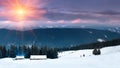 Colorful winter sunrise in the mountains. Fantastic morning glowing by sunlight. View of the snowy forest and old wooden hut cabin