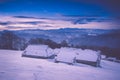 Colorful winter sunrise in the mountains. Fantastic morning glowing by sunlight. View of the snowy forest and old wooden hut cabin Royalty Free Stock Photo