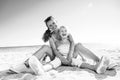 Happy trendy mother and daughter sitting on beach Royalty Free Stock Photo