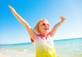 Happy trendy child in colorful shirt on seacoast rejoicing