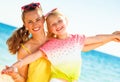 Smiling trendy mother and daughter on seashore having fun time