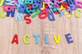 Colorful wooden alphabet and word ACTIVE. Top view on grey woo