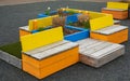 Colorful wooden benches in the urban city park. Furniture for garden. Wooden seater garden benches with flowerbed Royalty Free Stock Photo