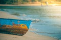 Colorful wooden fishing boat on sand beach with sea wave in the background in vintage style. Royalty Free Stock Photo