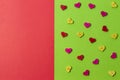 Colorful wooden heart buttons on greenery and red background