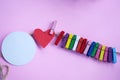 Colorful wooden paper clips with red heart and blank white circle paper for text note message attached on pink background. Royalty Free Stock Photo