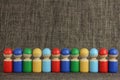 Colorful wooden toy people are lined up in a row, brown cloth or fabric  background with copy space Royalty Free Stock Photo