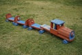 Colorful wooden train toy on the grass in a playground at daytime Royalty Free Stock Photo