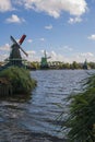 Colorful wooden windmills in the Zaanse Schans Museum stand on the river bank in Zaandam, the Netherlands, on a sunny day.
