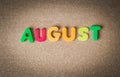 Colorful wooden word AUGUST on cork board with selective focus