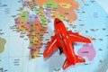 Colorful world map with airplane on it with the continents Africa, Europe, North America, Asia, South America, Australia and