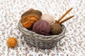 Colorful yarn in balls and coil and wooden needles lies in braided basket
