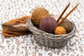 Colorful yarn in balls and needles lies in braided basket