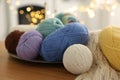 Colorful yarns and pattern sample on wooden table against blurred lights, closeup Royalty Free Stock Photo