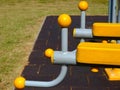 Yellow plastic exercise equipment detail in park. plastic grip on grey bent steel pipe frame.