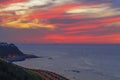 Colorful yellow purple crimson sunset over ocean with cumulus clouds. In background, a ship sails in haze, in foreground Royalty Free Stock Photo