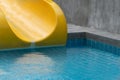 Yellow slider with blue swimming pool in summer time recreation background