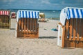 Colorfuled striped roofed chairs on sandy beach in Travemunde. A blurred couple sitting on beach in background. Lubeck Royalty Free Stock Photo