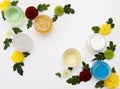 Colorfull jars with green, white, yellow. blue paint and yellow spring flowers in the corners on white background with copy space