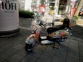 A colorfully designed white ladies scooter standing on roadside