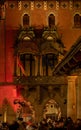 The colorfully illuminated facade of the town hall with a large group of people enjoying