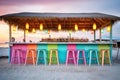 colorfully lit beach bar with empty stools