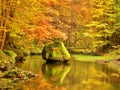 Colors of autumn mountain river. Mossy boulder in cold water