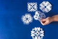 Background of various Christmas themed snowflakes cut out of white paper on a trendy blue background 2020 with a gift Royalty Free Stock Photo