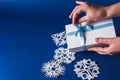 Background of various Christmas themed snowflakes cut out of white paper on a trendy blue background 2020 with a gift Royalty Free Stock Photo