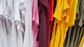 Colors of rainbow. Variety of casual shirts, t-shirts on hangers in a store. Cloth cotton of various bright colors close-up.