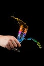 Colors splash - splash of rainbow colors liquid from a glass in the hands on a black background Royalty Free Stock Photo