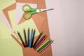 Colour paper, scissors, school stationery supplies, pencils, paint, and ruler lying on table. Origami DIY tutorial for kids