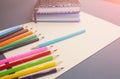 Colour pencils with notebooks and lying on pastel beige background. Back to school concept sign written. Colorful art studying and