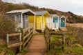 Coloured huts above a beach with boadwalk for access Royalty Free Stock Photo