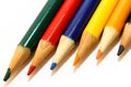 Coloured pencils in colours green, red, blue, yellow, orange and black, aligned side by side in a closeup macro photo isolated Royalty Free Stock Photo