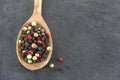 Coloured pepper on a wooden spoon isolated on slate Royalty Free Stock Photo